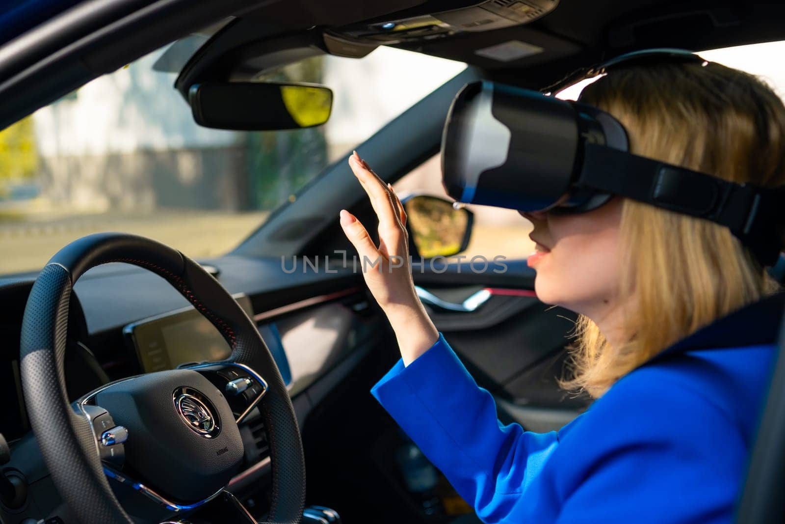 Business woman in the VR googles sitting in the car and turning the steering wheel in a car. Having fun and playing games with augmented reality, May 2022, Prague, Czech Republic