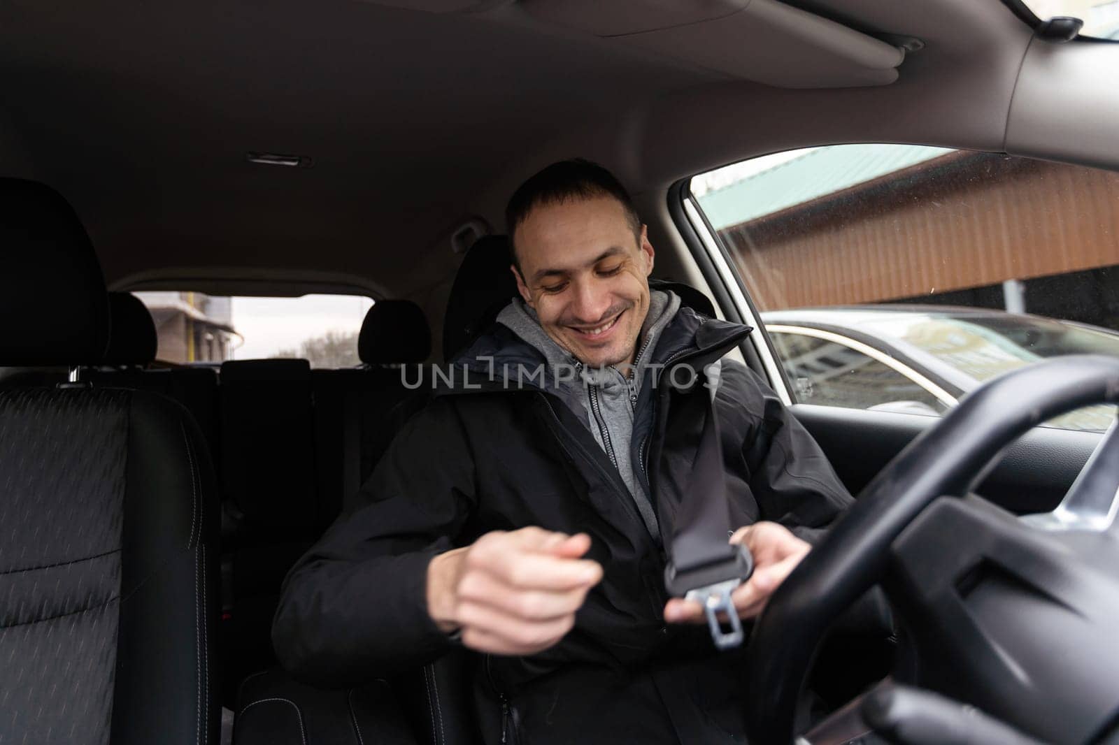 Success in motion. Handsome young man in full suit smiling while driving a car. High quality photo