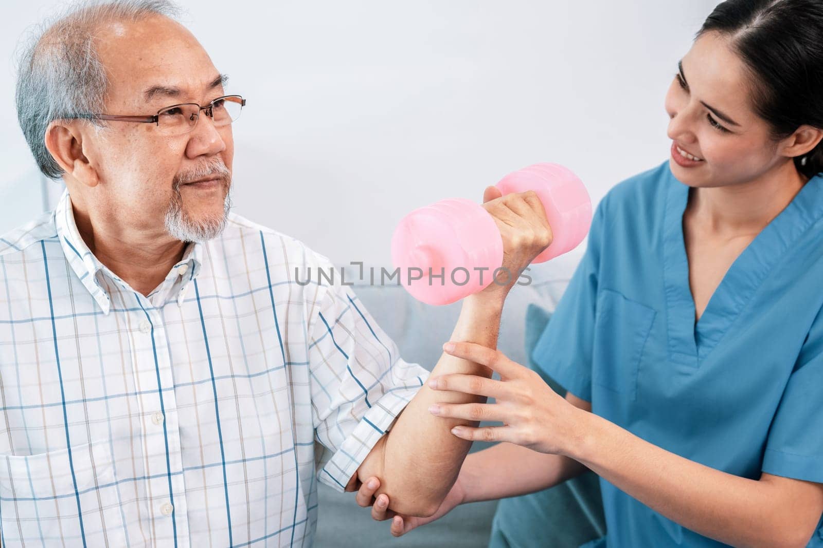 Contented senior patient doing physical therapy with the help of his caregiver. Senior physical therapy, physiotherapy treatment, nursing home for the elderly