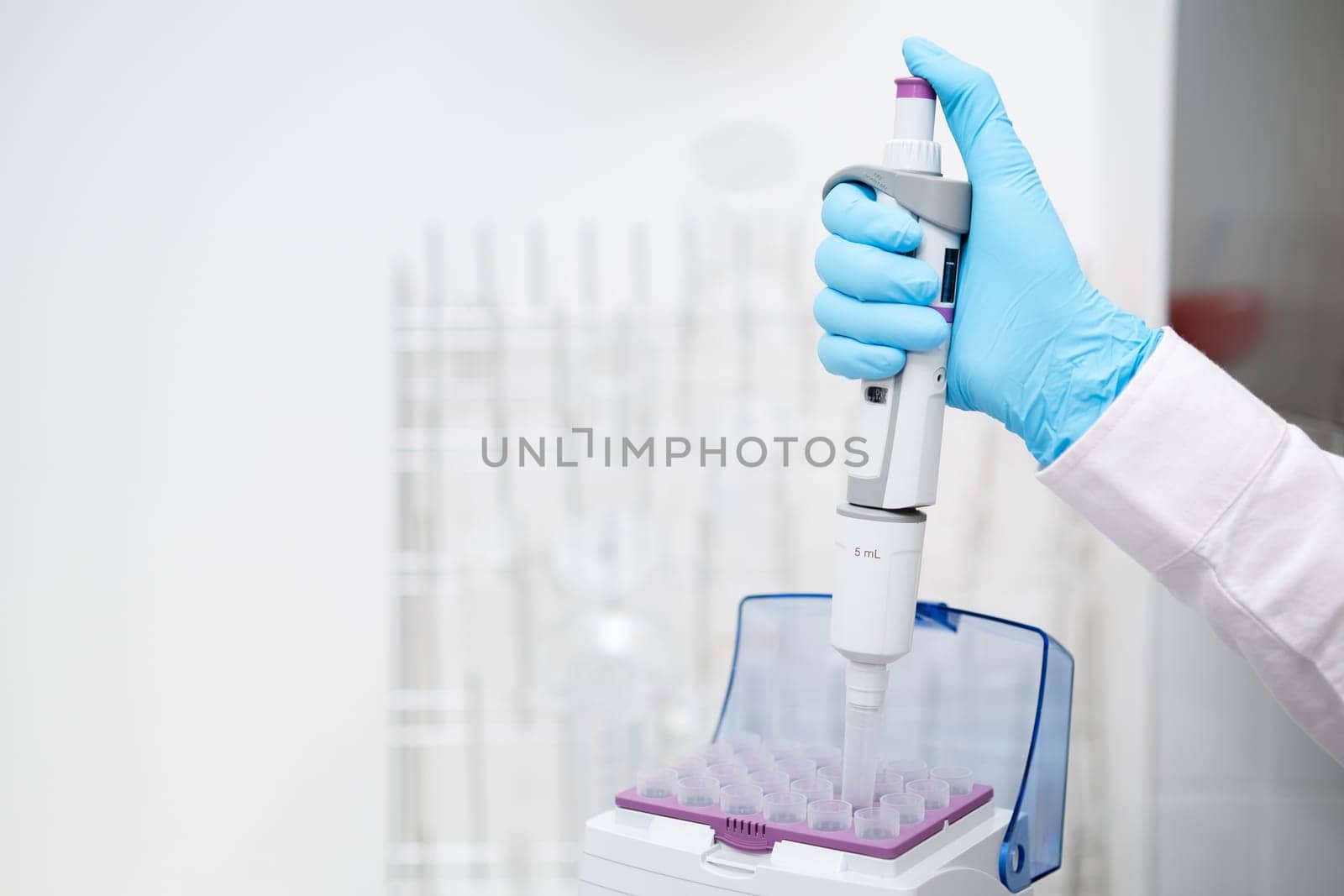 Close up scientist hand takes plastic tip for automatic pipette from the box for sample collection. Medical research laboratory.