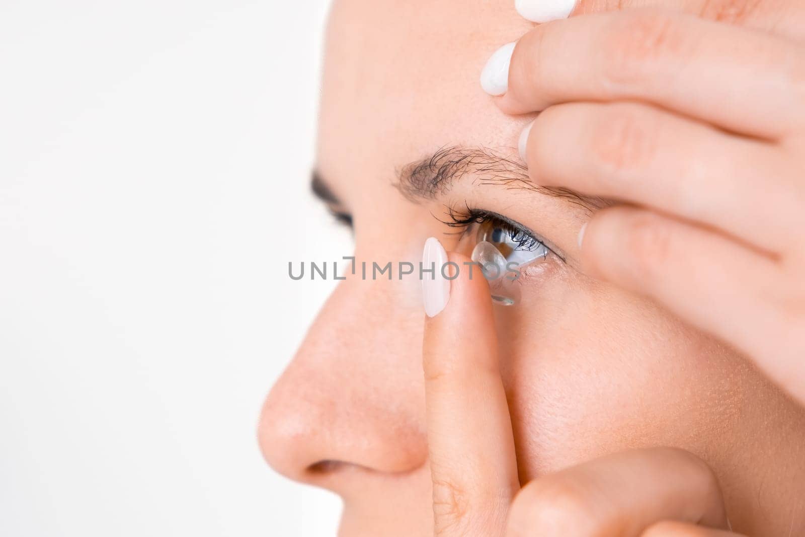 Side view of young woman applying contact lenses. Better vision concept.