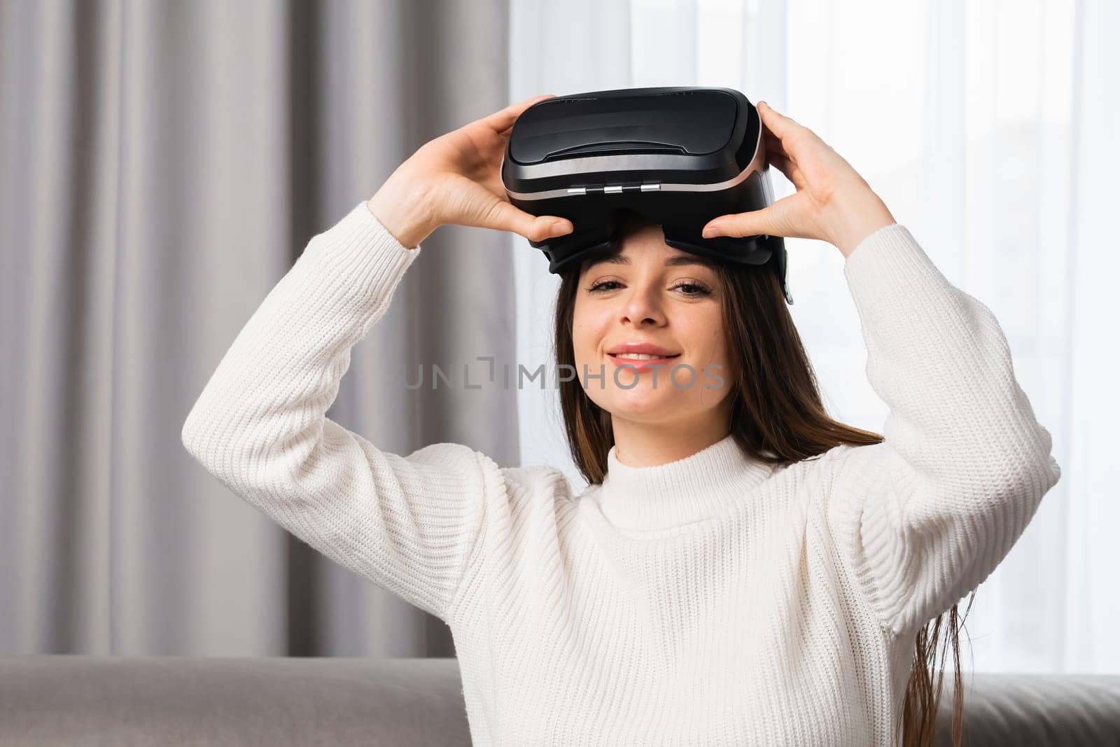 A smiling beautiful woman puts on VR glasses for playing games. Entertainment and innovative technology concept.