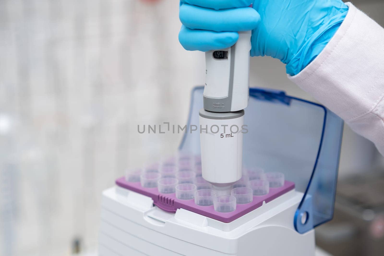 Close up scientist hand takes plastic tip for automatic pipette from the box for sample collection. Medical research laboratory.