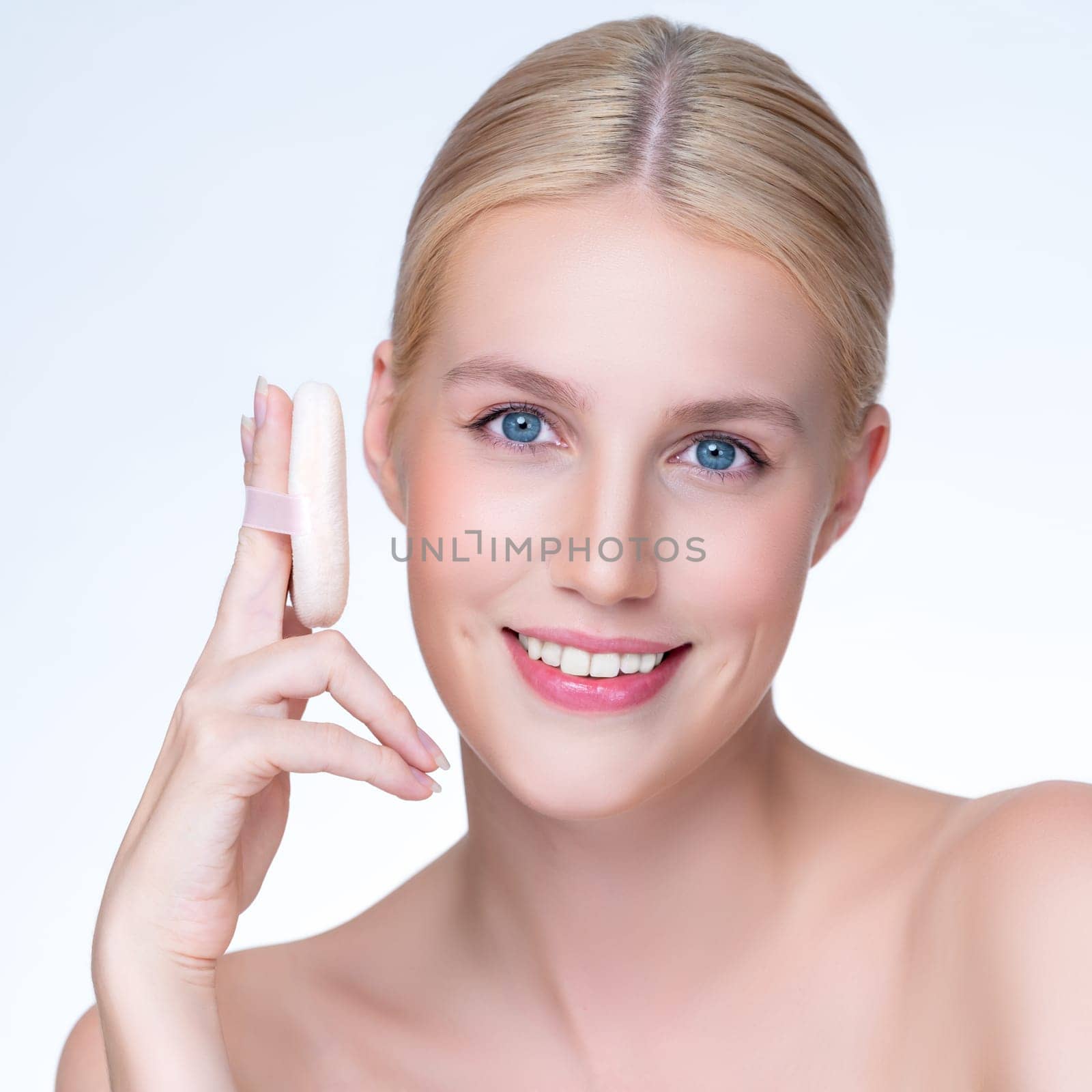 Closeup personable beautiful natural soft makeup woman using powder puff for facial makeup concept. Cushion foundation applying on young girl face in isolated background.