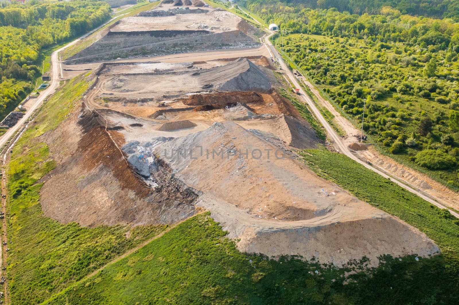 Quarry for mining of natural resources on the hill close to the forest, aerial view