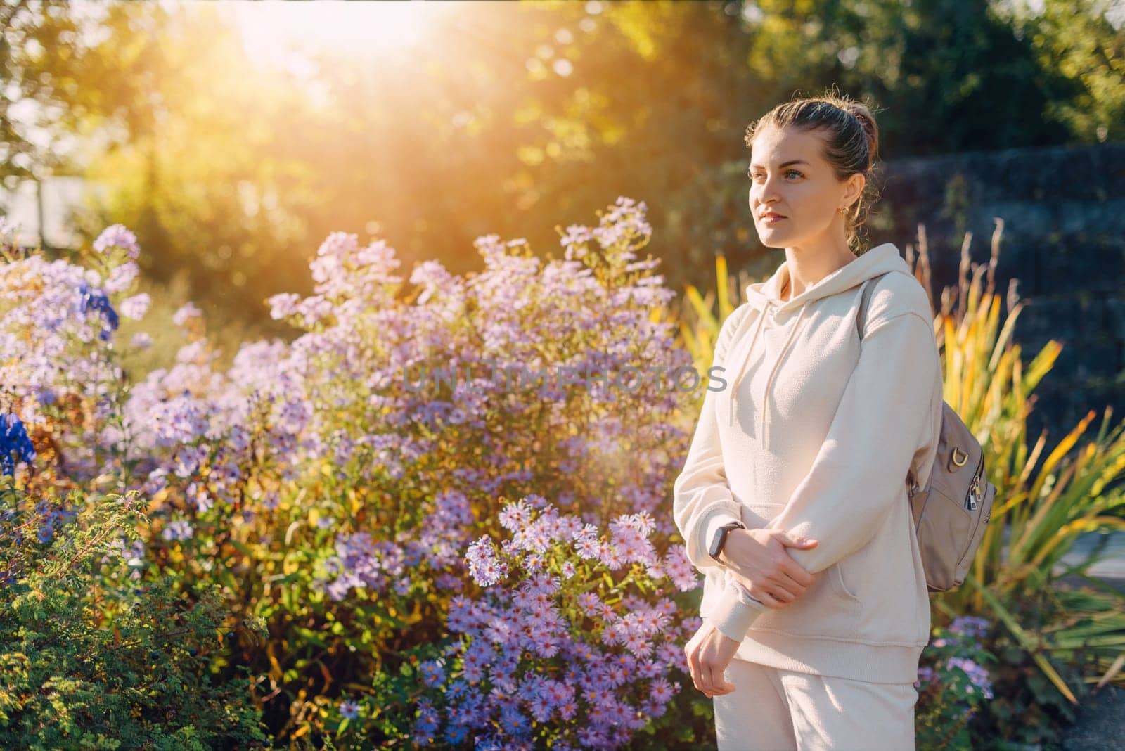 Beautiful elegant woman standing in autumn park with yellow leaves outdoor. Beauty Romantic Girl Outdoors enjoy autumn yellow leaves. Portrait of joyful woman in park during fall. Happy ng nature. Sun light on sunset. Warm toned art work. Portrait of romantic female by Andrii_Ko