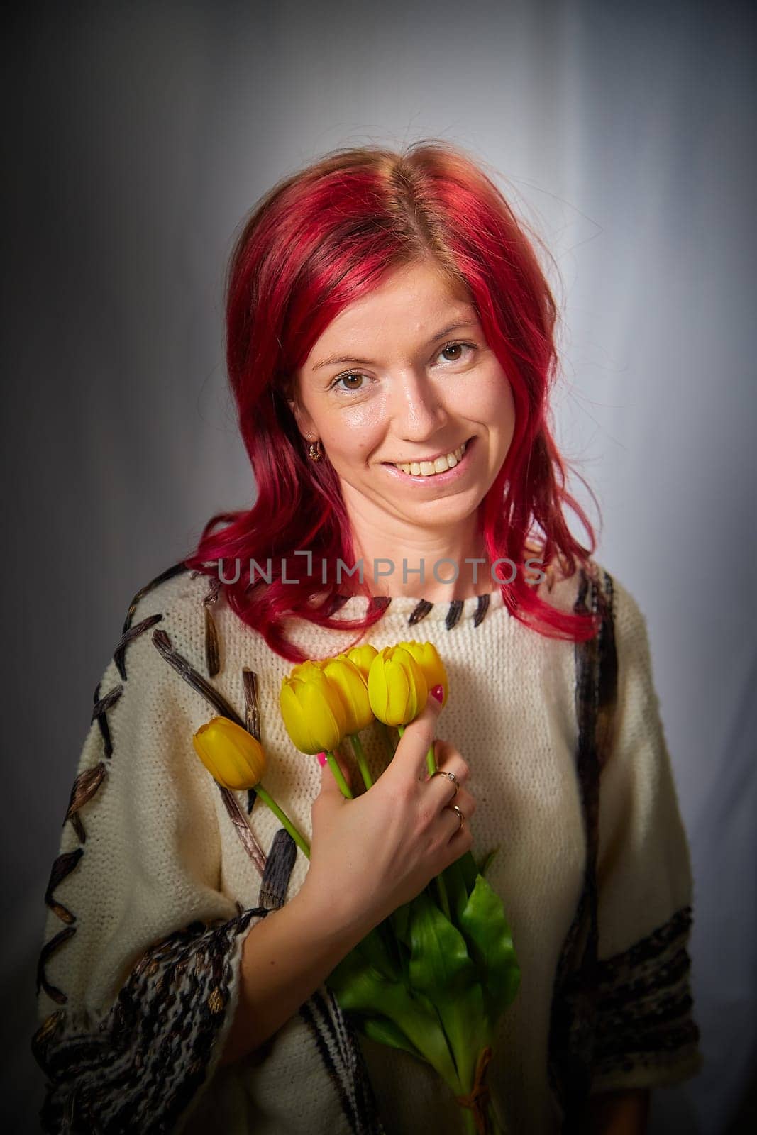 Beautiful woman with red hair on light background holds tulips. Inernational woman's day 8 March