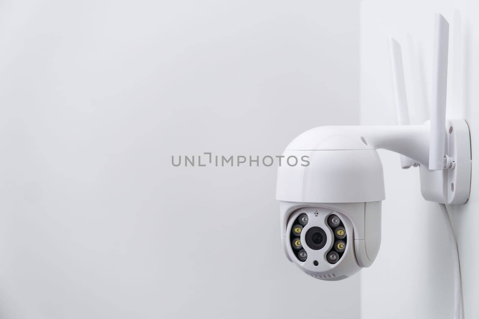 Round CCTV camera with antennas shoots video on the white wall. Digital equipment to record and broadcast real time video closeup