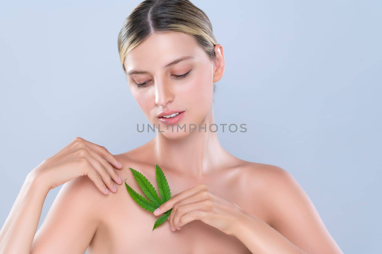 Alluring beautiful woman model portrait holding green leaf as concept for cannabis skincare cosmetic product for skin freshness treatment in isolated background.
