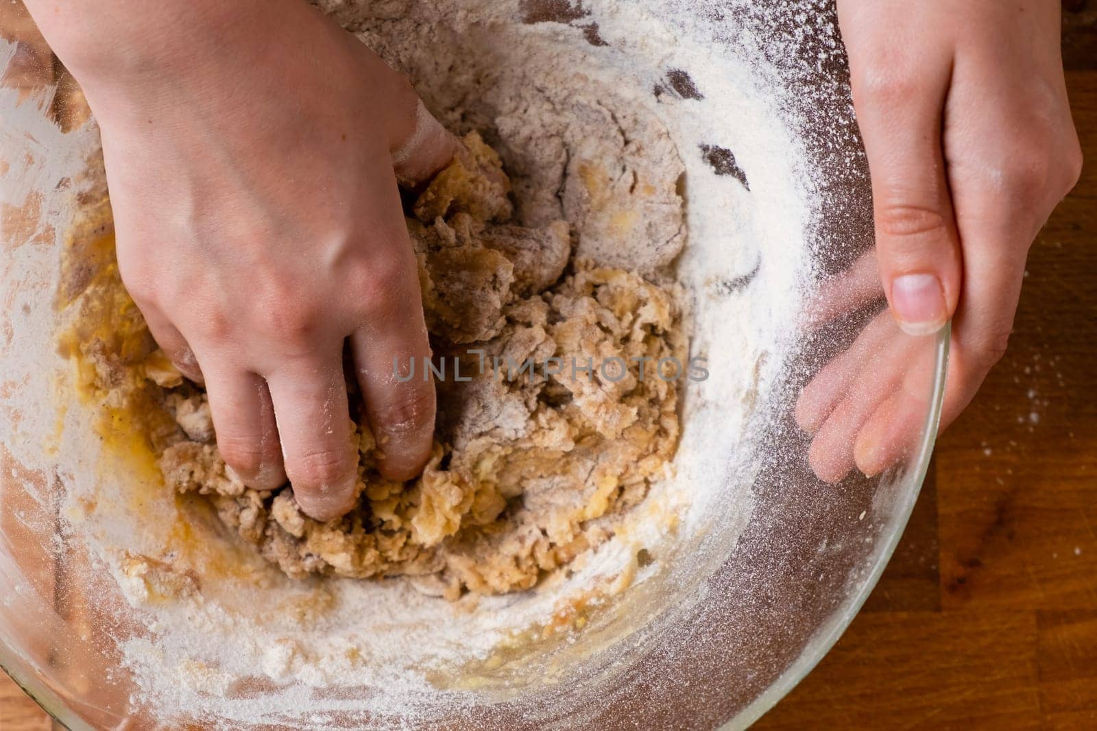 Close up of woman baker hands kneading the dough in the mixing bowl. Homemade pastry for cakes or cookies.