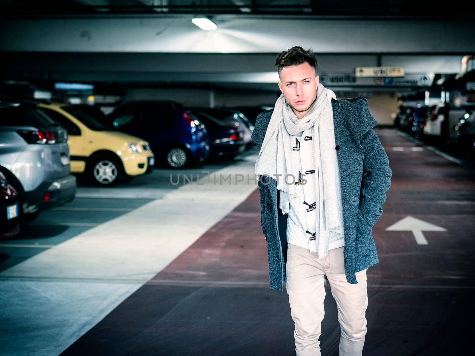 Handsome man in casual clothing on background of indoor parking lot