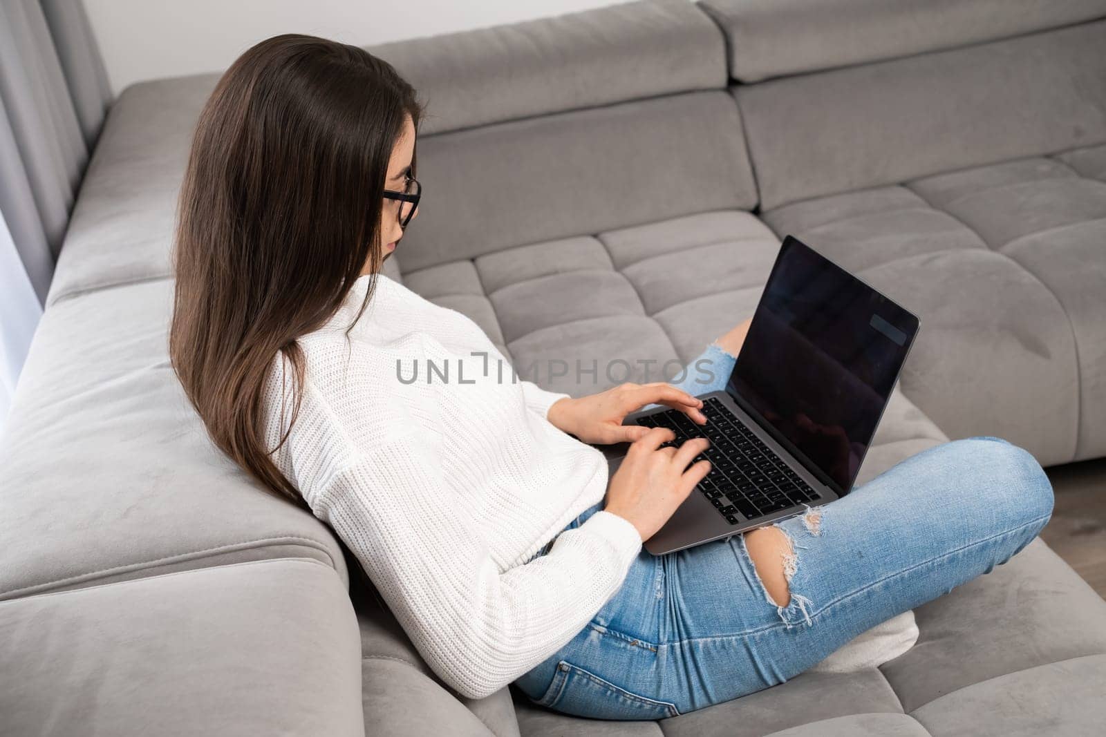 Top view of young girl sitting in the living room and working remotely