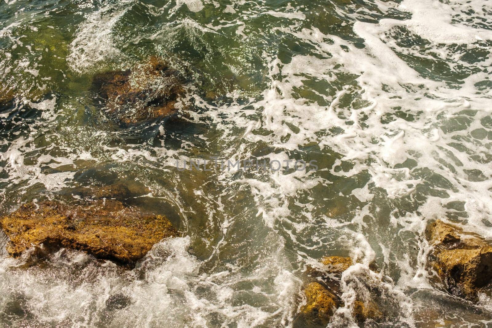 Sea waves breaking on rocks and hitting the shore.