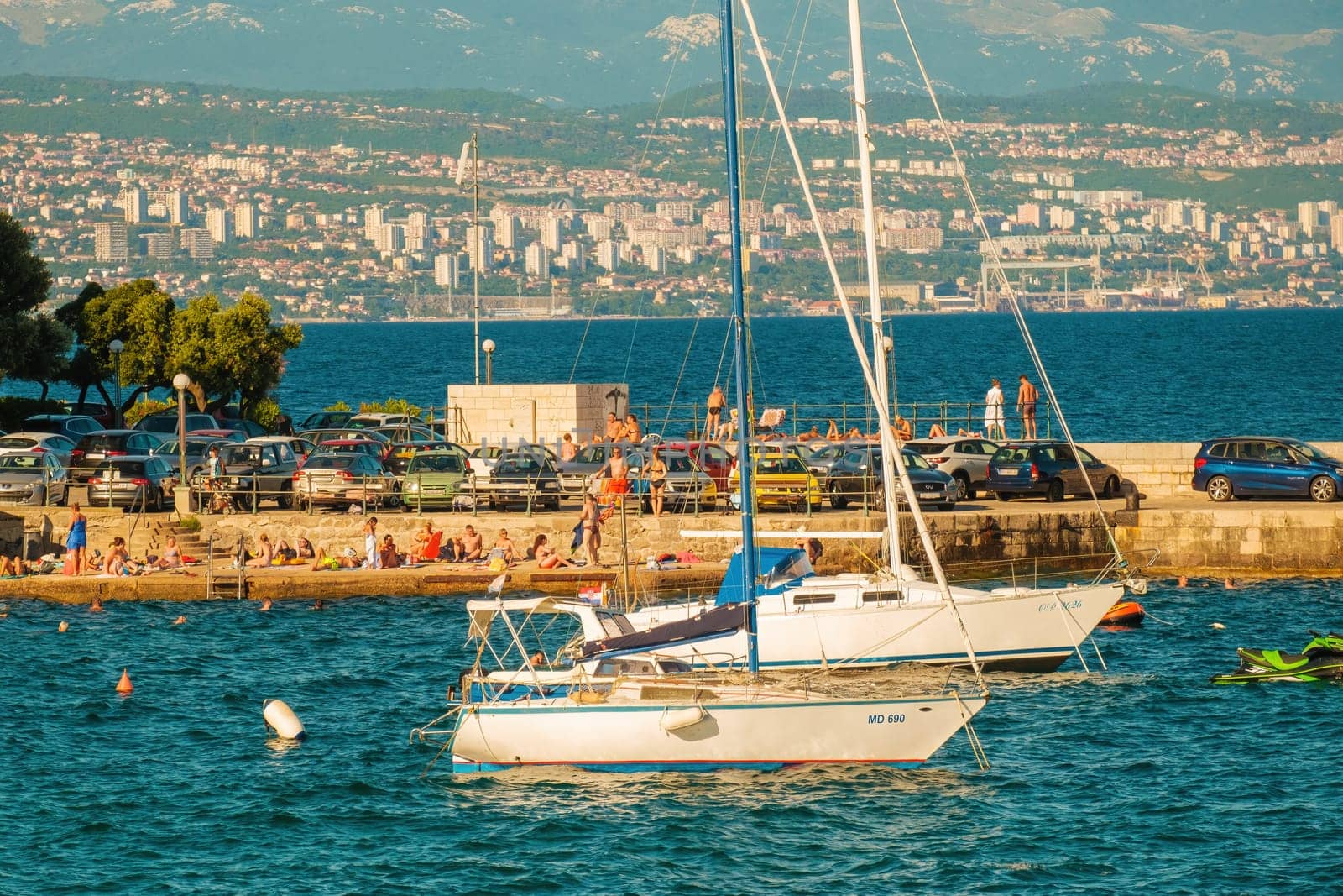 Boats drift on water by sea stone pier with people and cars by vladimka