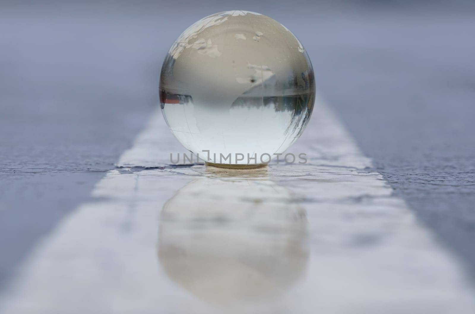 Glass globe on wet asphalt with markings. Globalization concept.