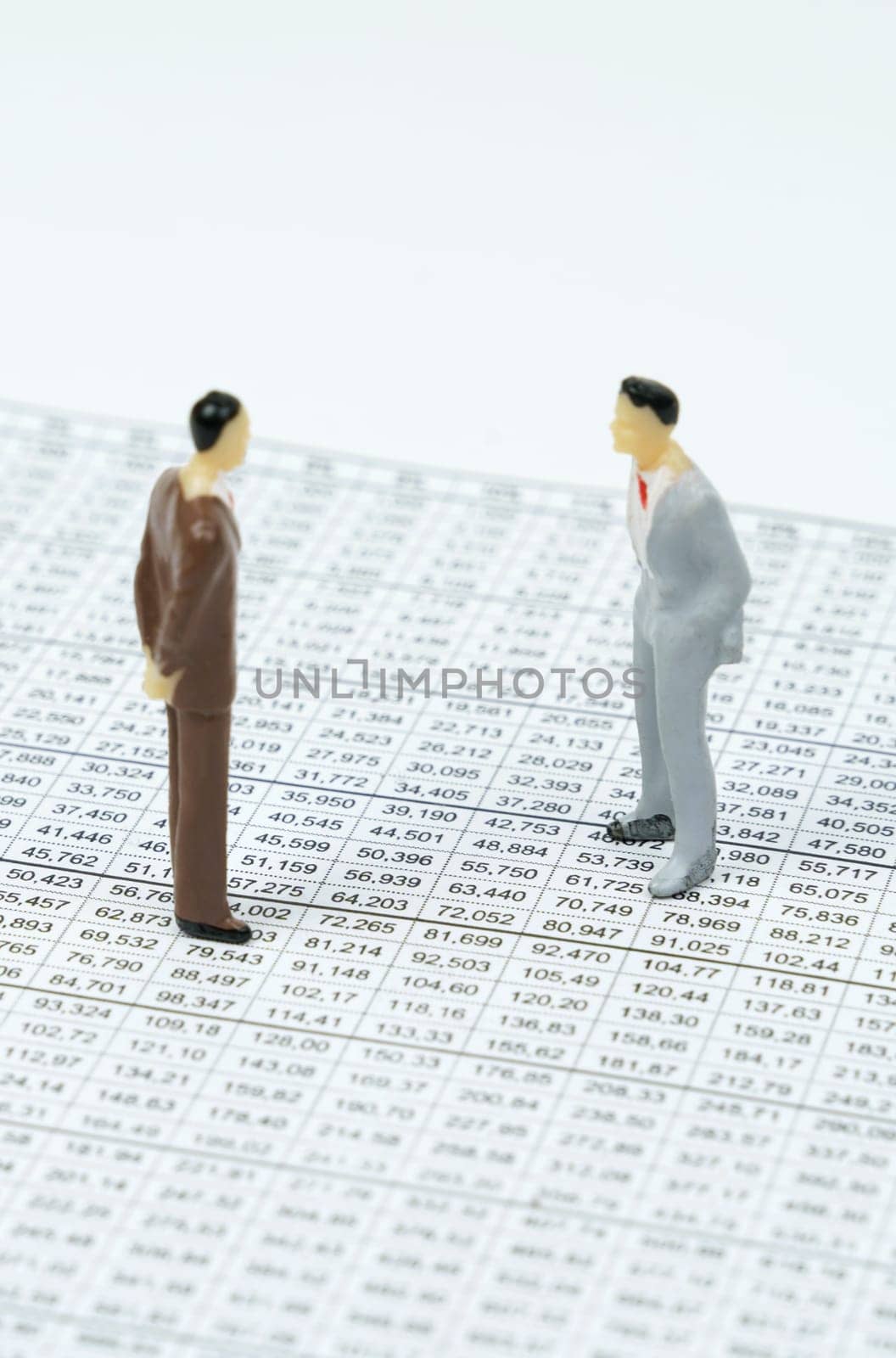 Business concept. There are miniature figures of businessmen on financial reports with figures - they are talking.