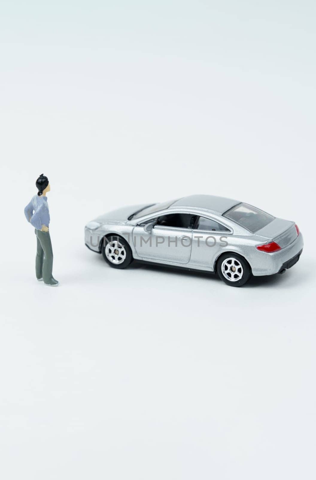 Industry and technology concept. On a white surface is a car and a miniature figurine of a man looking at the car.