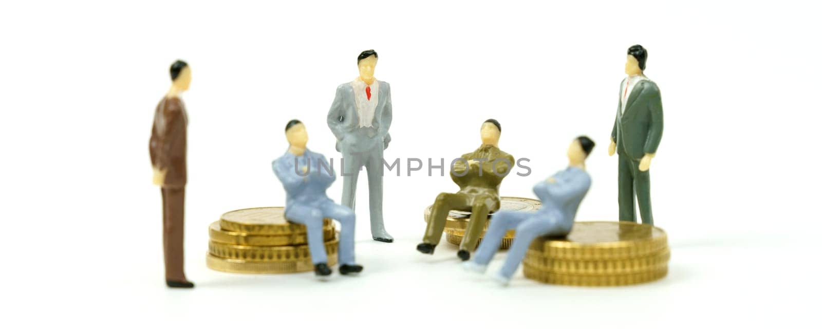 Business and finance concept. On the white surface on the coins and next to them are miniature figures of businessmen conferring.