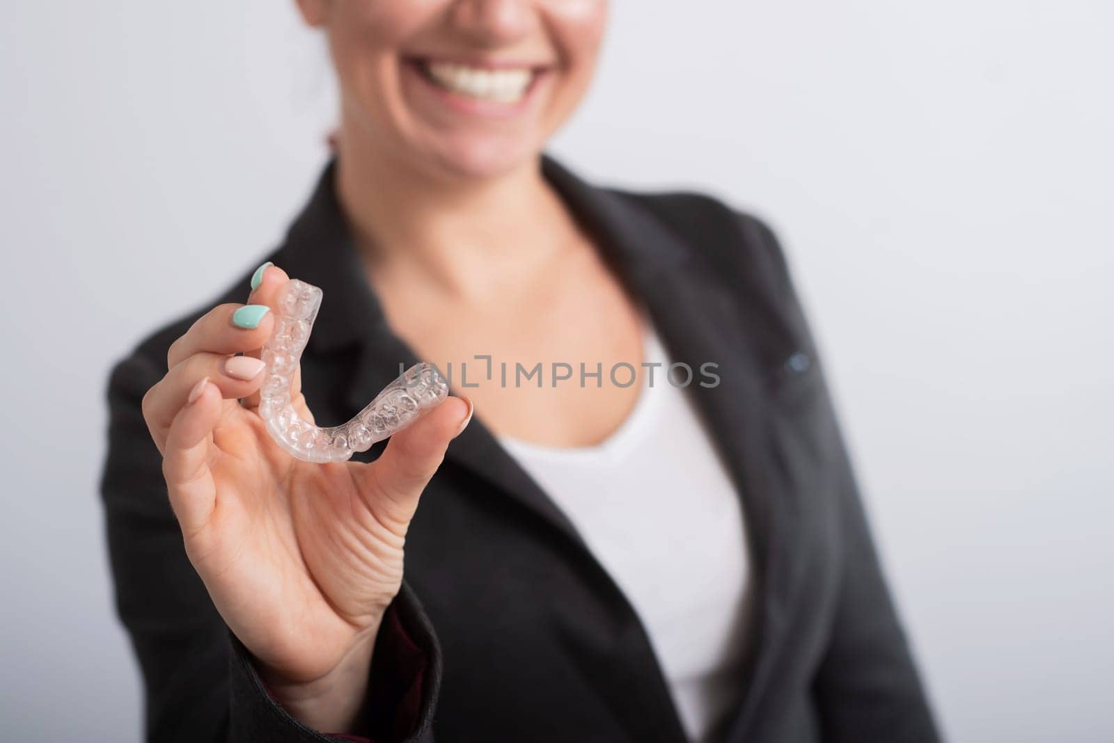 The woman is smiling and holding a transparent plastic aligner for bite correction by mrwed54