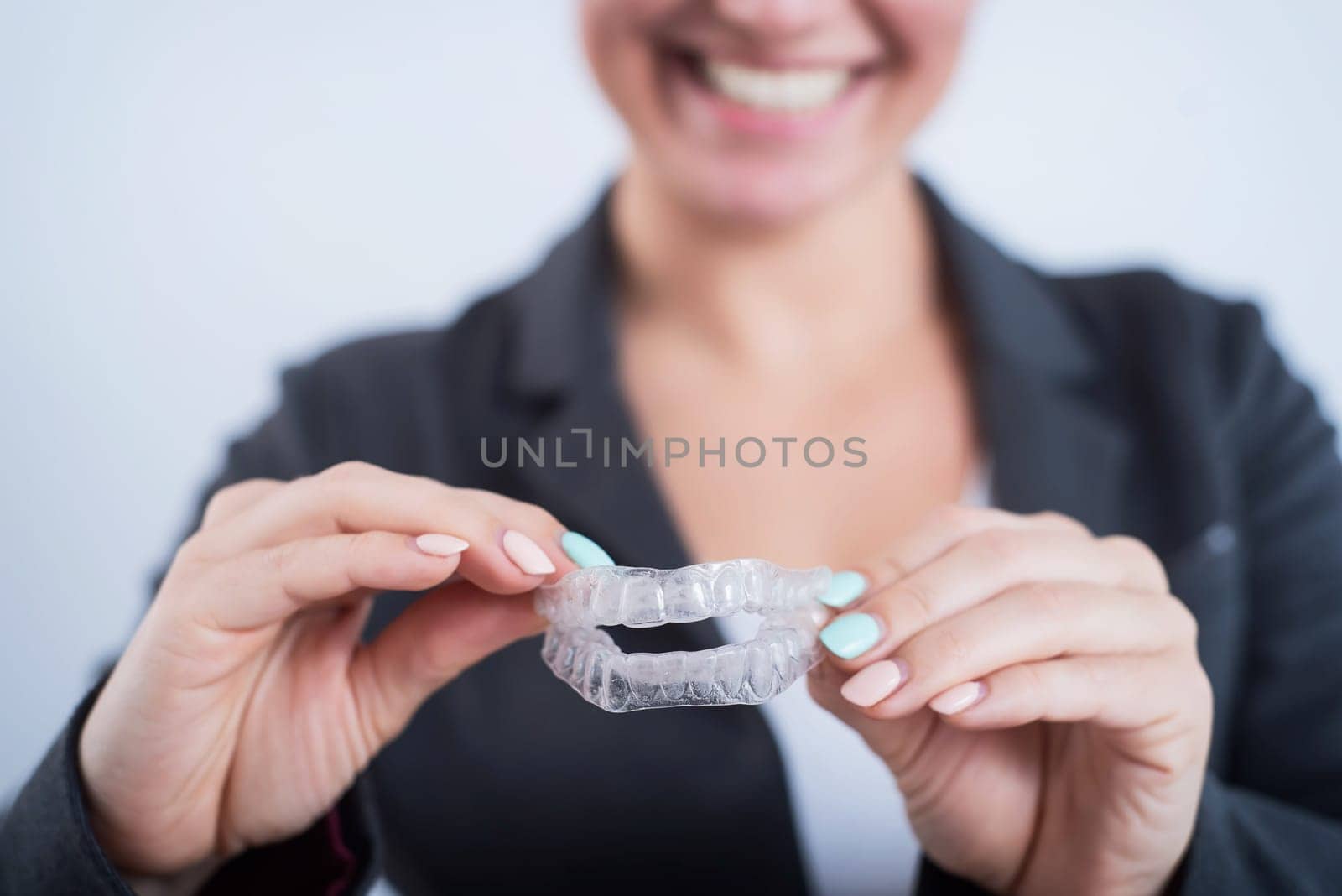 Smiling business woman holding two transparent aligners by mrwed54