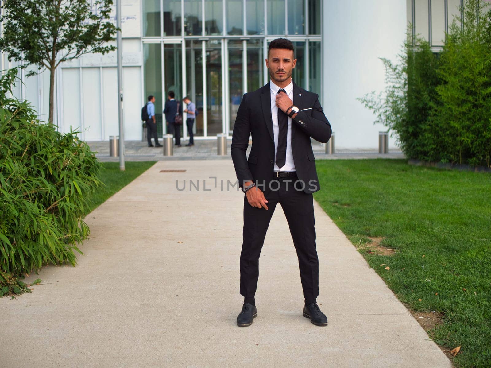 Portrait of stylish young man wearing business suit, standing in modern city setting