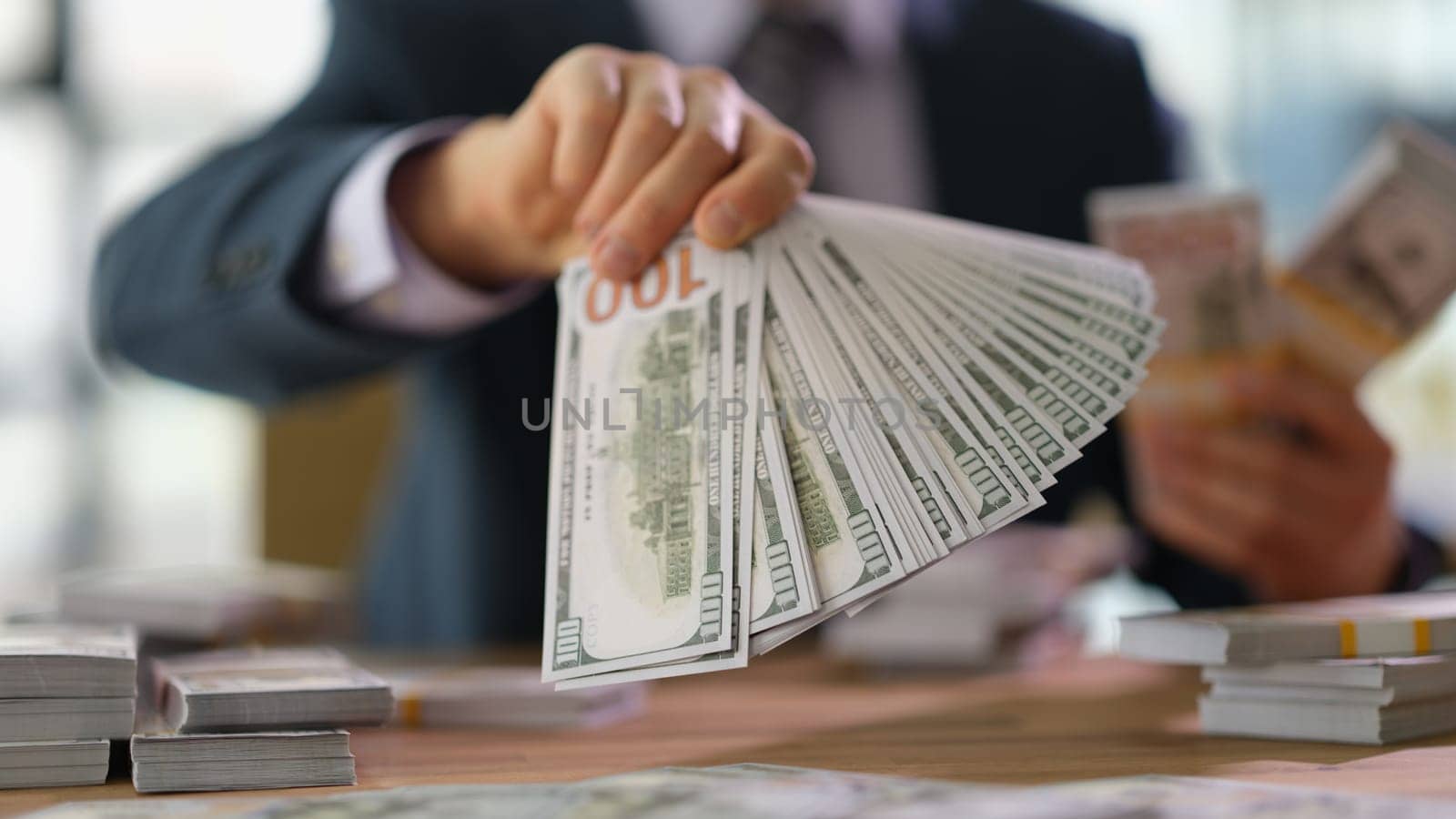 Businessman hand holding lot of money dollar banknotes in fan closeup. Black bookkeeping and bribery concept