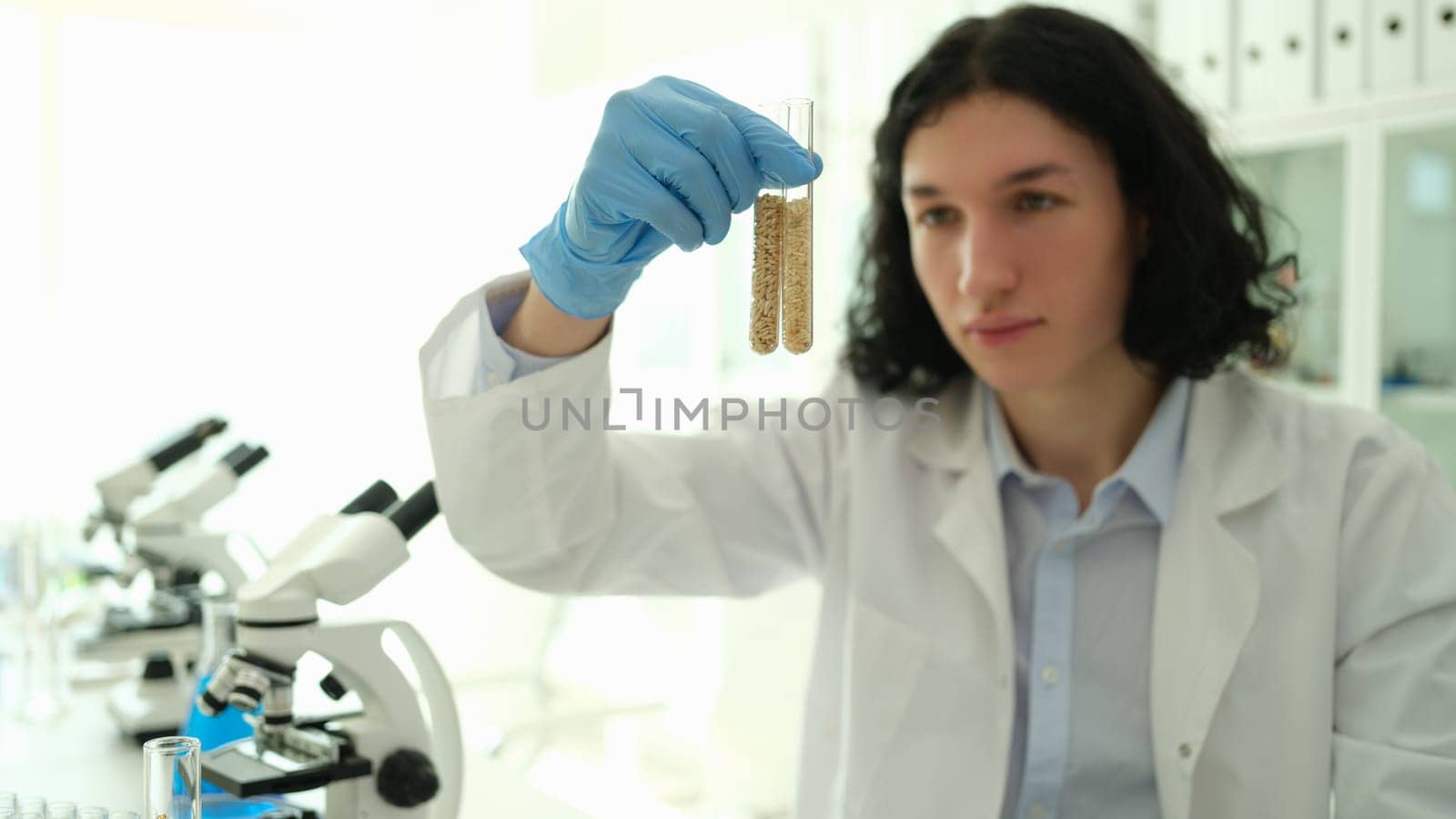 Chemist scientist holding test tubes with grains in laboratory closeup. Selection and development of fertilizers for plants concept