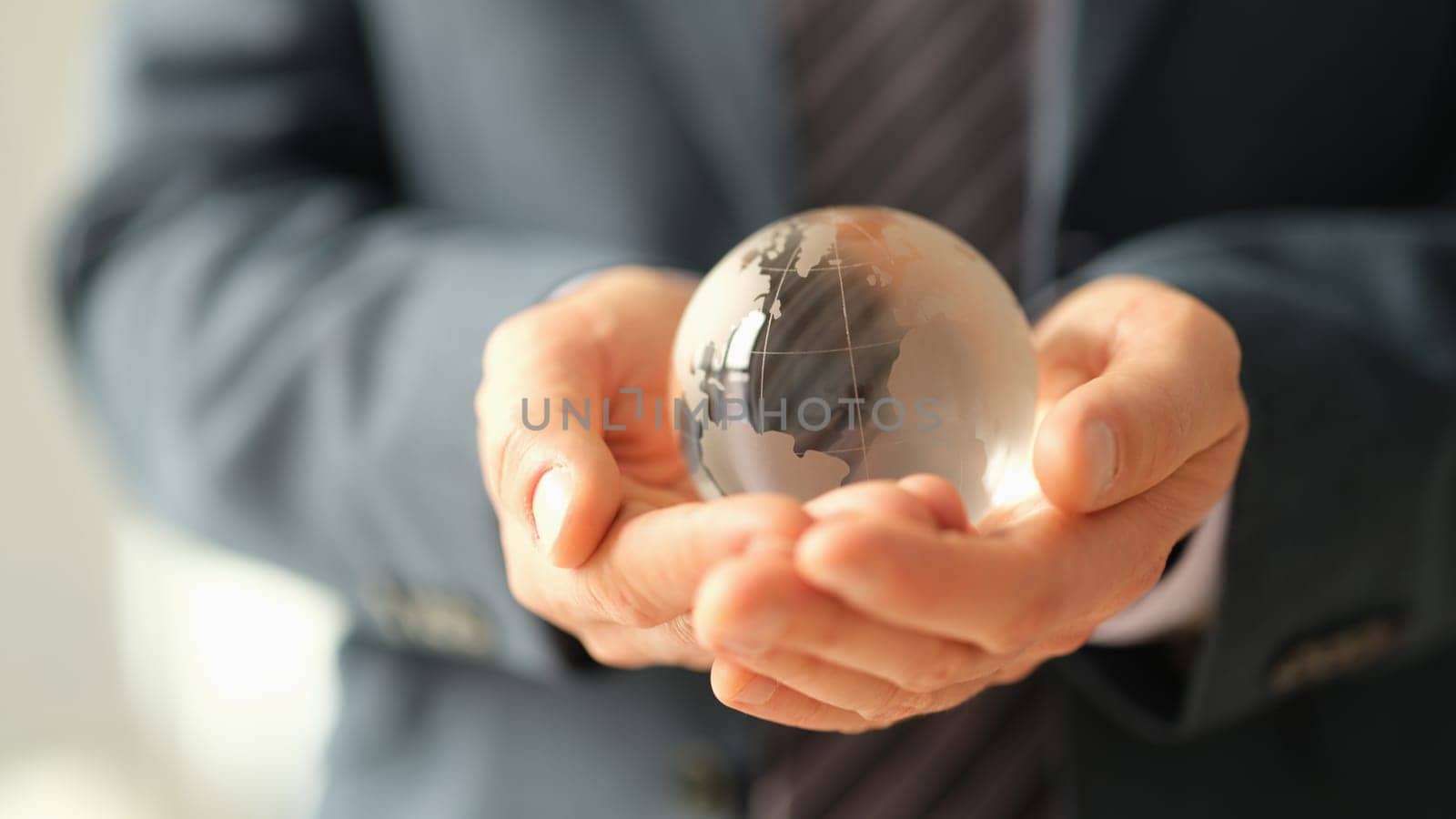 Businessman in jacket holding glass ball with world map closeup. Global economic crisis and sanctions concept