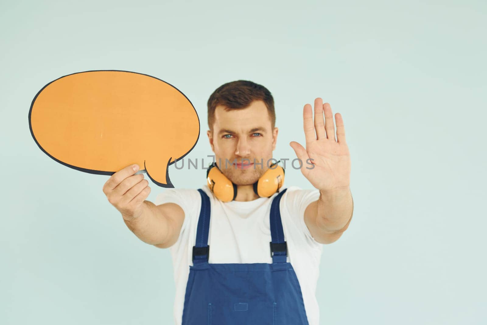 With big headphones on neck. Man standing in the studio with empty signs for the text.