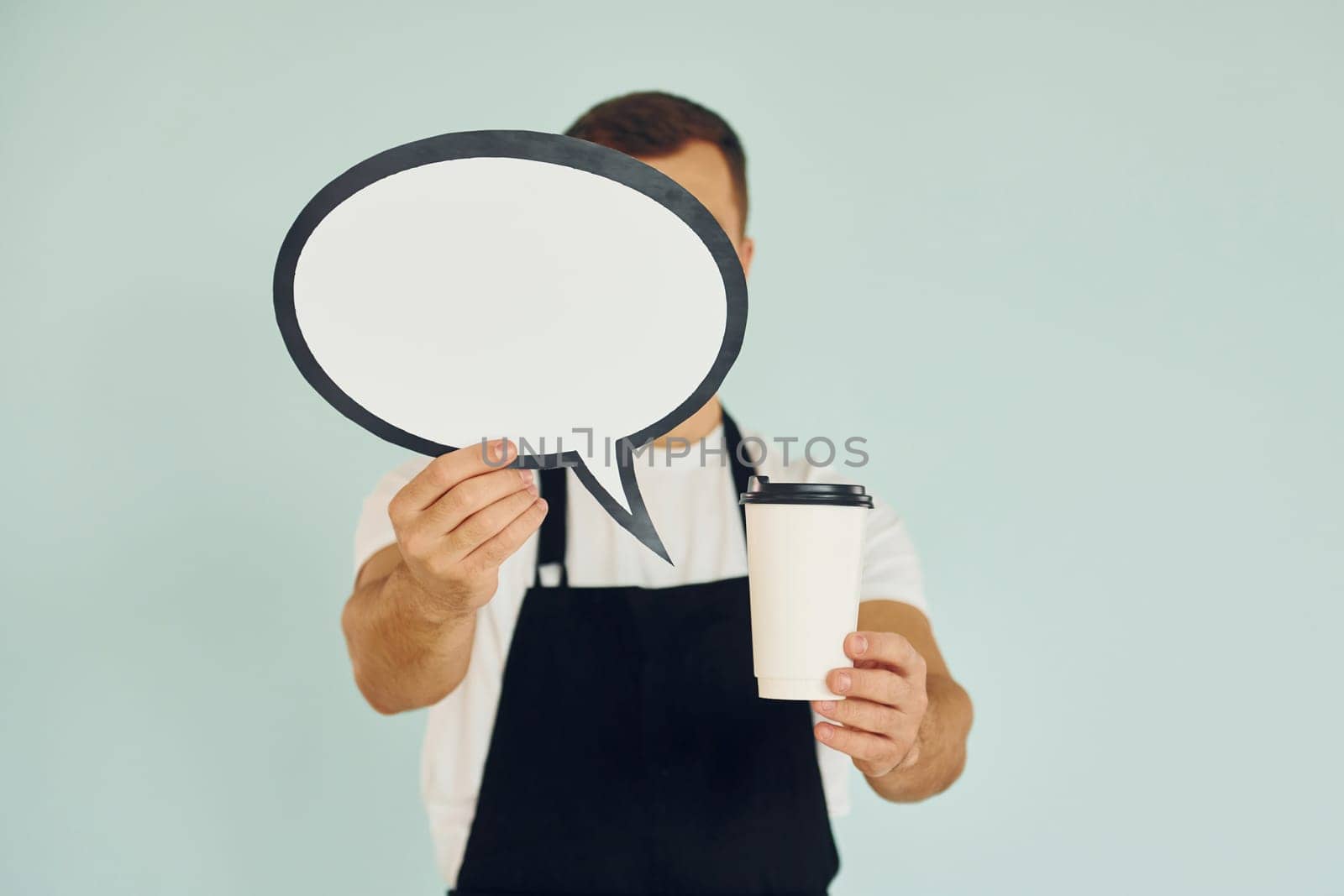 Holding drink in hand. Man standing in the studio with empty signs for the text.