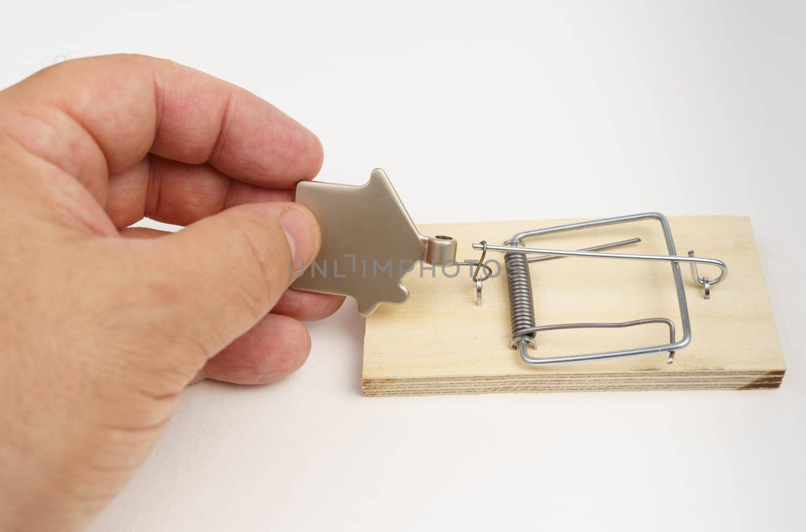 A man's hand is trying to pull a metal figurine of a house out of a mousetrap. by Sd28DimoN_1976