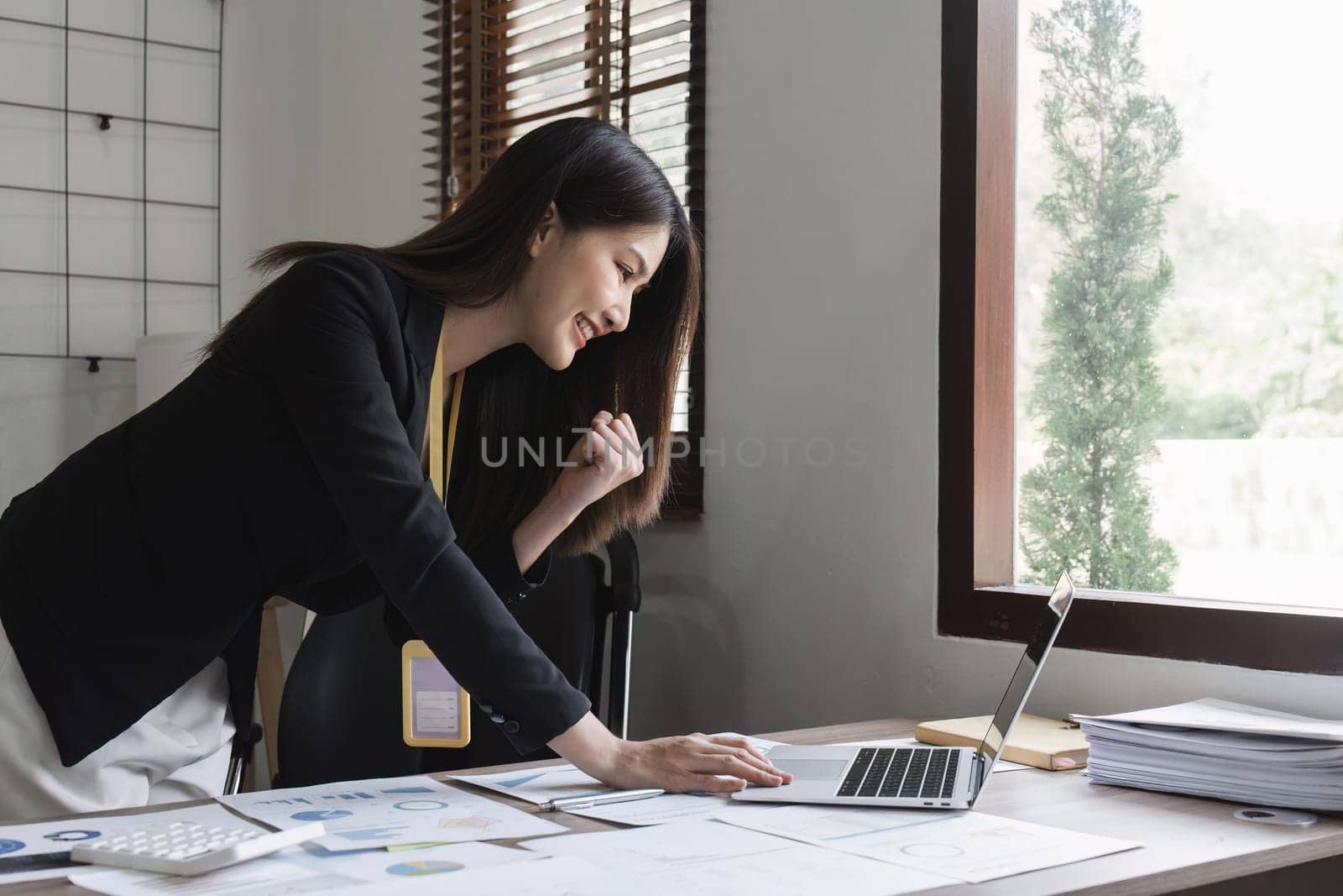 Success at work, good deal. Asian business woman looks at the laptop screen, screams excitedly and raises his fists in a victory gesture.