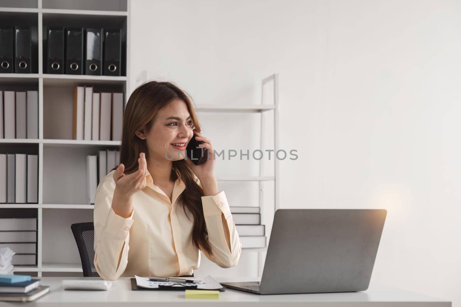 Business woman talking on a phone call in office. Happy female professional calling her associates on a mobile phone by nateemee