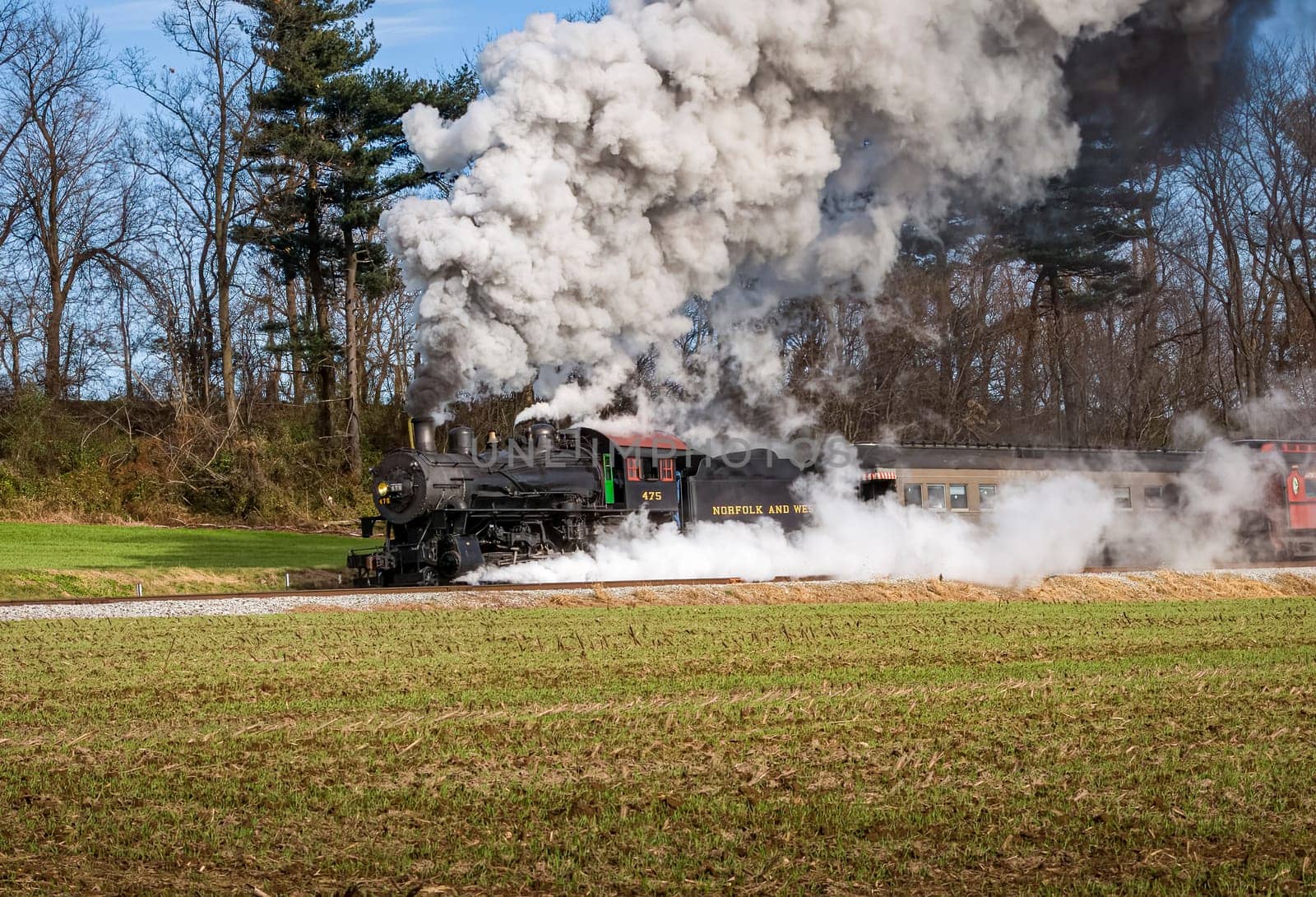 Ronks, Pennsylvania, December 4, 2022 - A View of a Classic Steam Passenger Train, Blowing Lots of Smoke and Steam, While Traveling in the Countryside on an Autumn Day