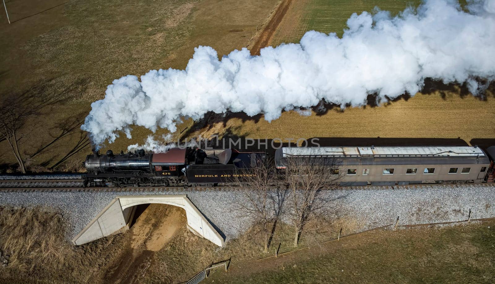 Ronks, Pennsylvania, December 28, 2022 - Aerial Parallel View of a Restored Antique Steam Passenger Train Traveling Thru The Countryside on a Sunny Autumn Day