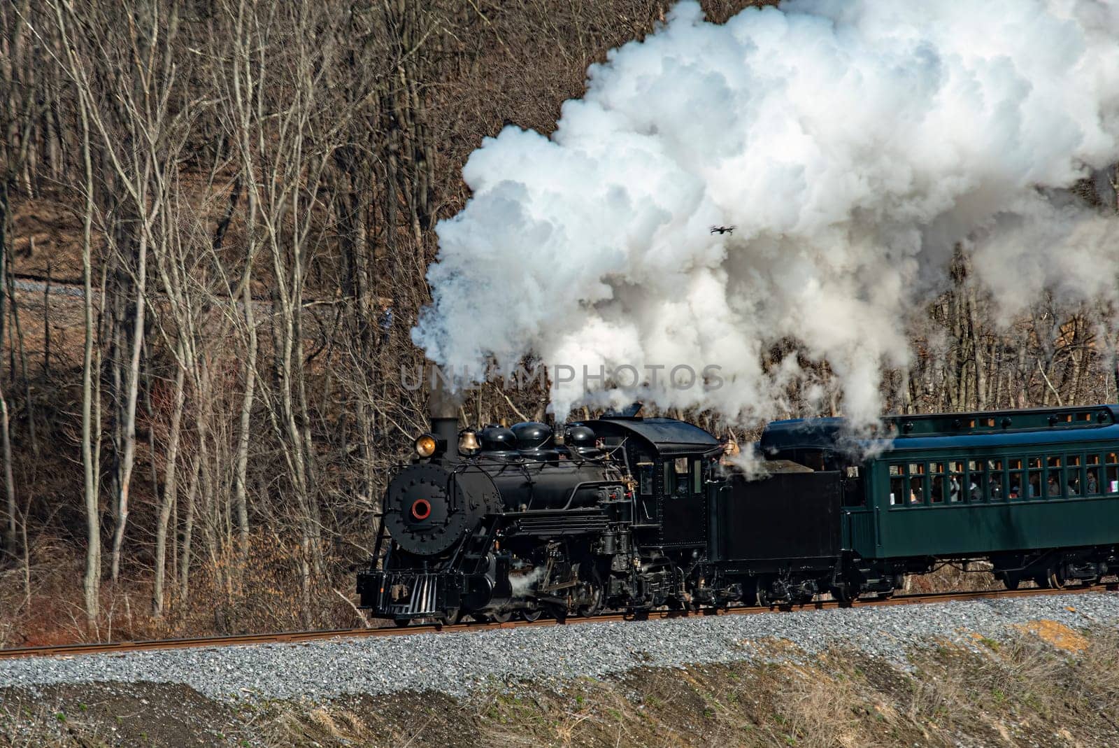 View of a Narrow Gauge Restored Steam Passenger Train Blowing Smoke and Traveling Thru Farmlands on a Winter Day