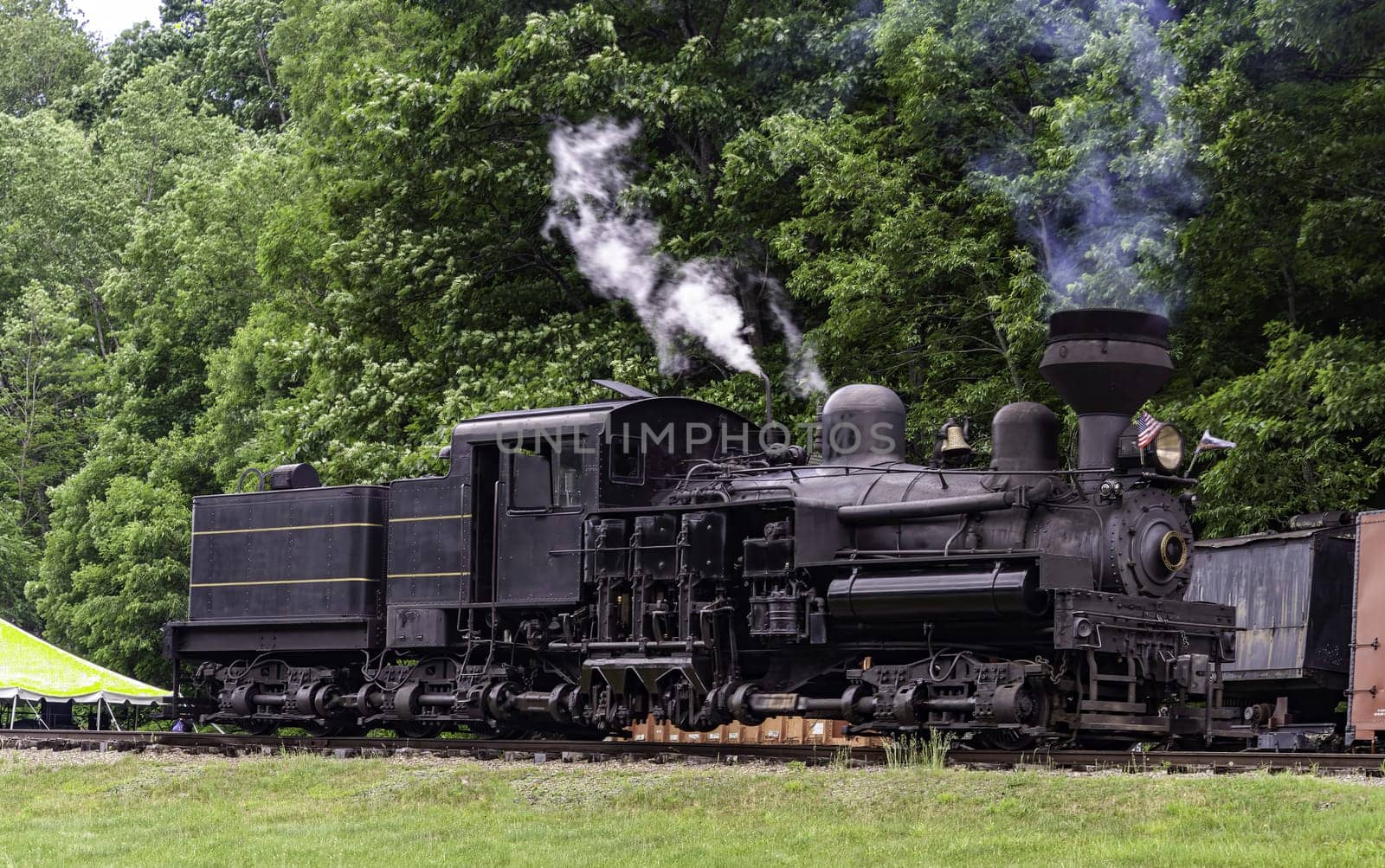 An Antique Shay Steam Engine, Traveling by Itself, Blowing Smoke and Steam on a Rail Road Track, on a Summer Day