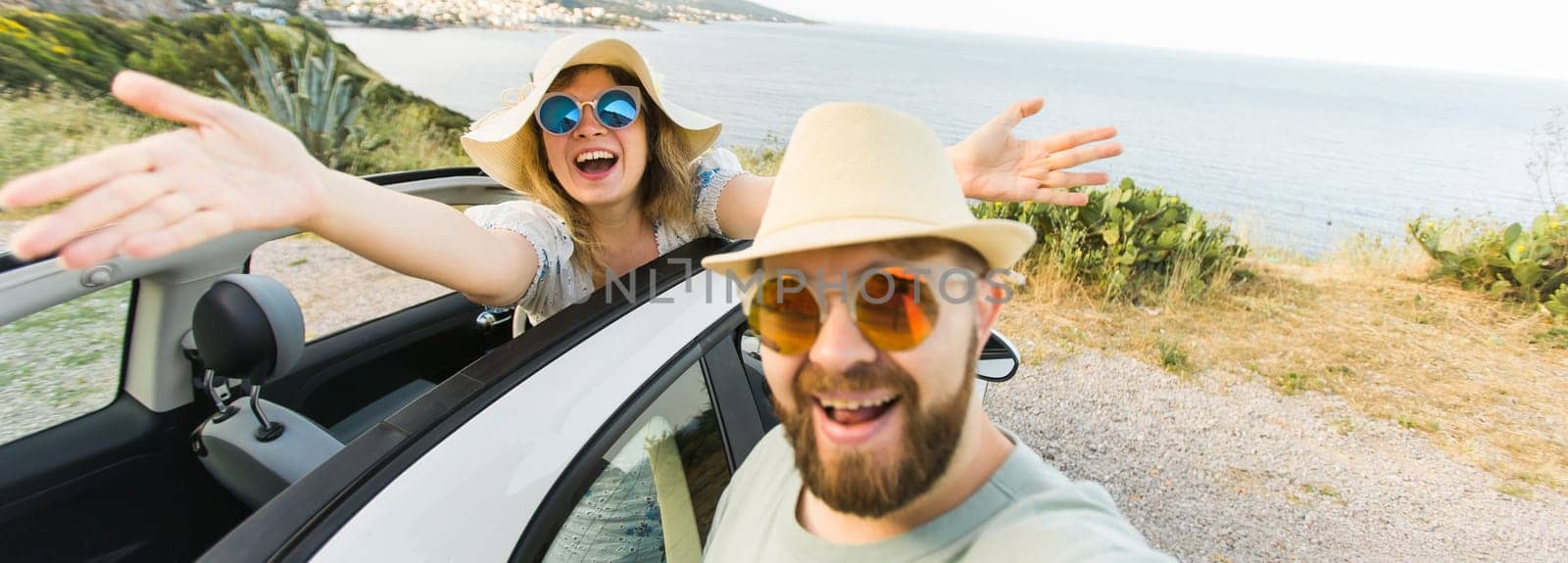Banner Happy beautiful couple in love taking a selfie portrait driving a convertible car on the road at vacation. Rental cars and vacation by Satura86