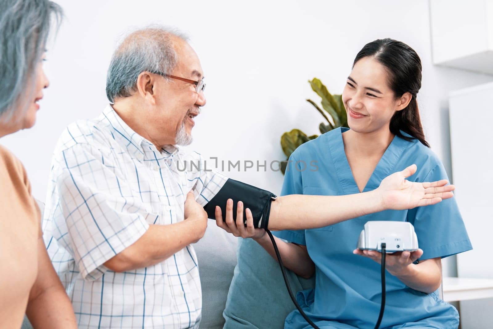 An elderly man having a blood pressure check by his personal caregiver by biancoblue