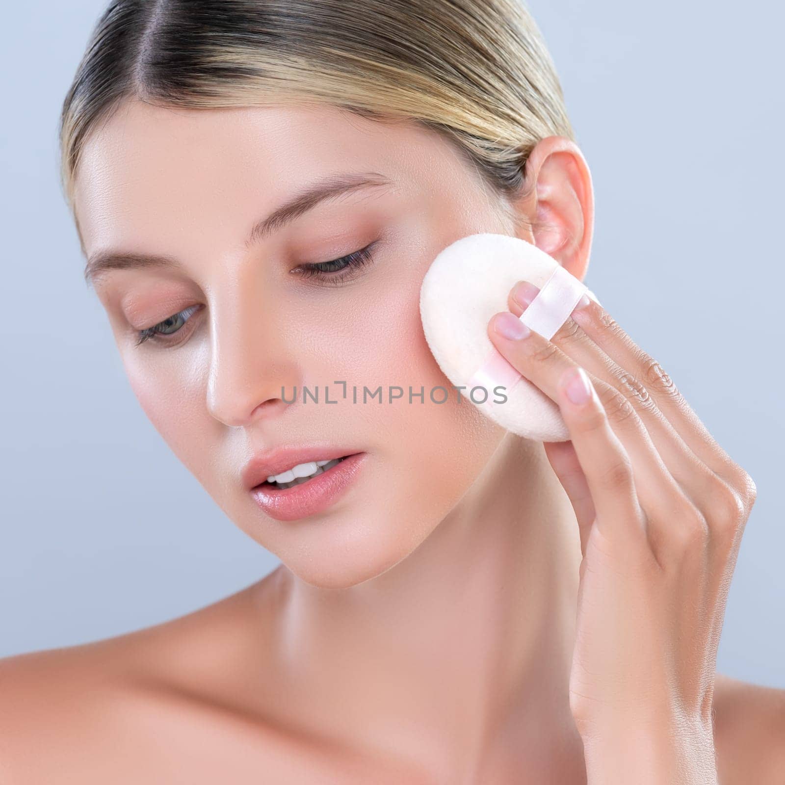 Alluring beautiful female model applying powder puff for facial makeup concept. by biancoblue