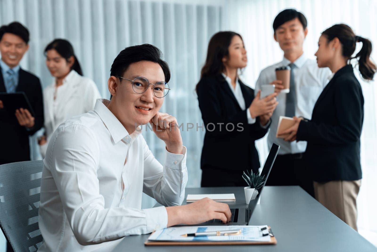 Portrait of focus young successful confident male manager, executive wearing business wear in harmony office arm crossed with blurred meeting background of colleagues, office worker.