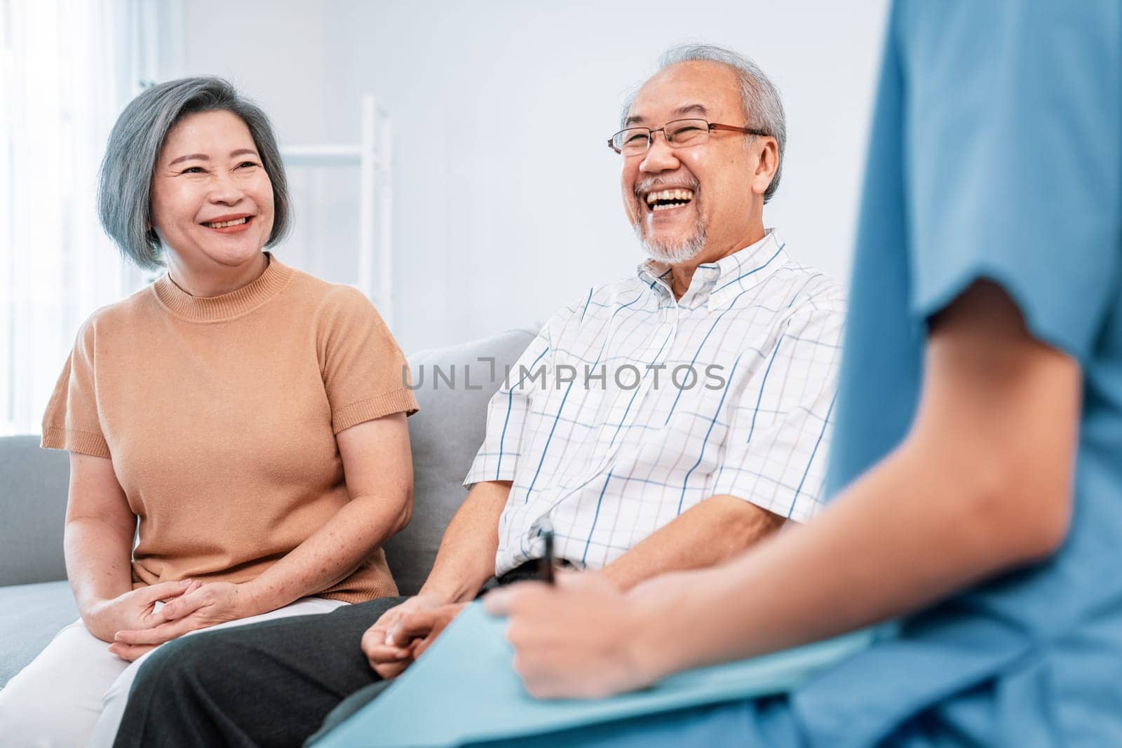 Female doctor visiting and talking to her contented senior couple at their home by biancoblue