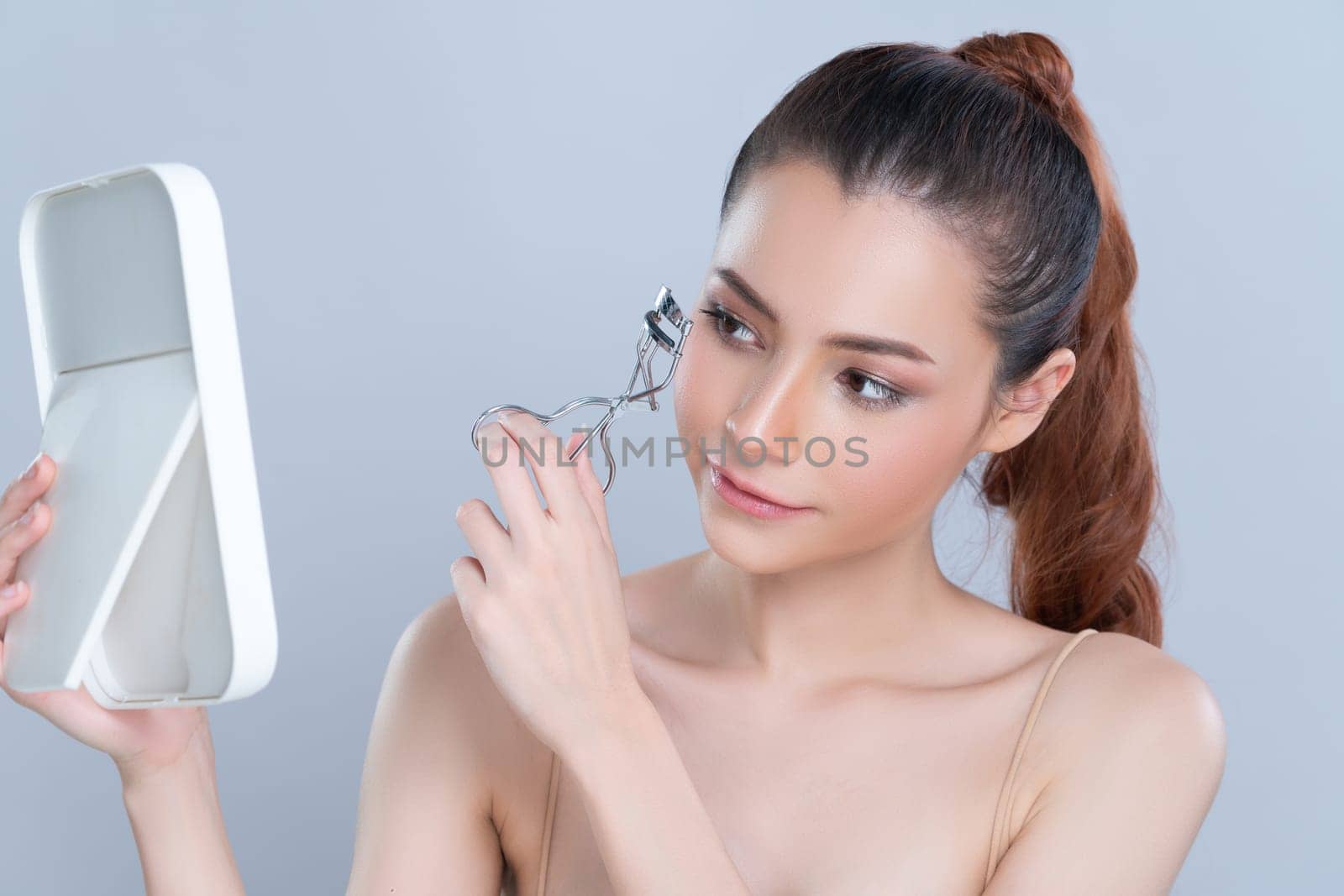 Closeup glamorous facial makeup, beautiful woman with perfect smooth cosmetic clean skin correct eyelash curler with metal mechanic beauty accessory in isolated background.