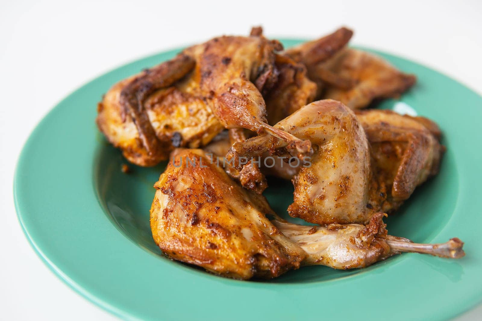 Delicious grilled fried quails lie on a green plate. Delicious and healthy meat. by sfinks