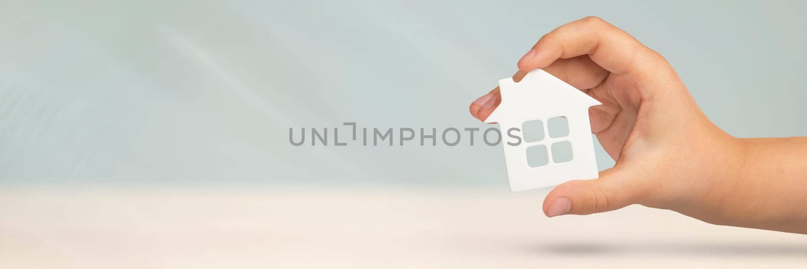 Real estate insurance. Model of a white house in hands on a gray blurred background. Insure a house or apartment, the concept of insurance services, with copy space by SERSOL