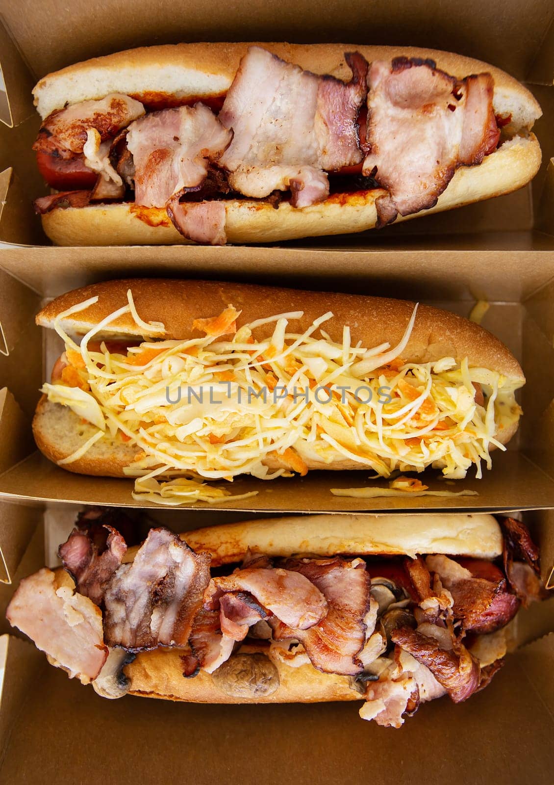 American hot dog with different flavors, with cheese and crispy onions on a white table in a minimalist style. Fast food, takeaway food, food for motorists. Hot dog sandwich with sausage, vertical photo. by sfinks