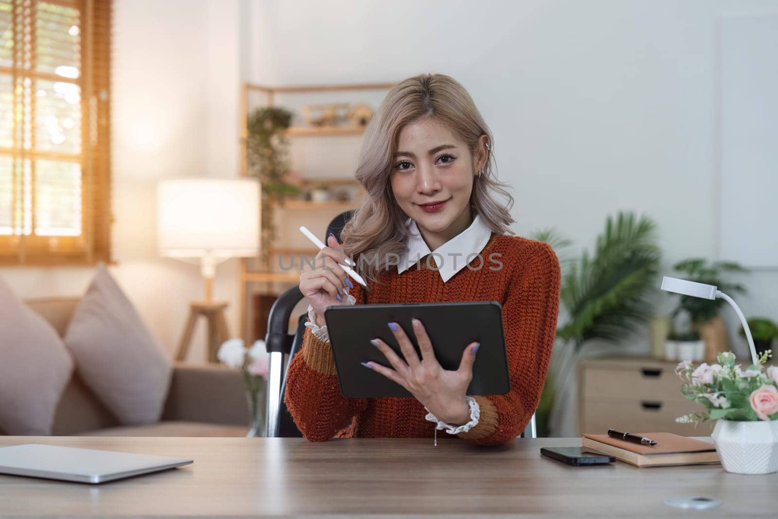 Woman using tablet on desk of her at home.