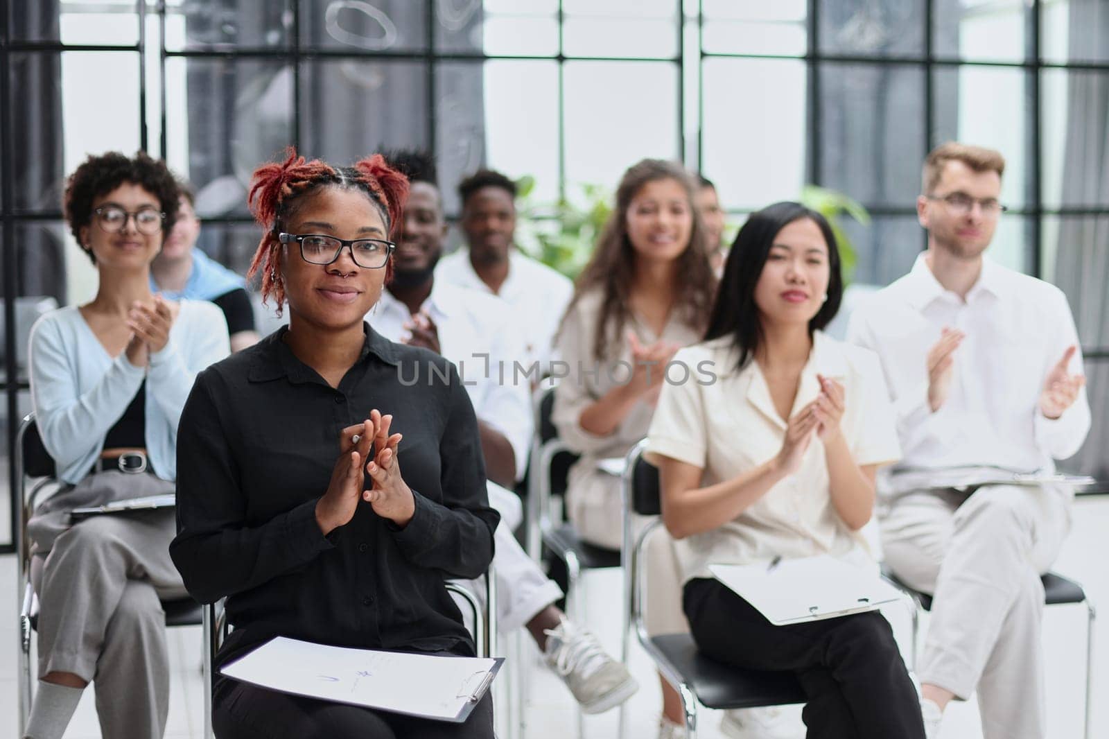 Selective focus of young businesswoman applauding together with interracial colleagues during seminar, banner