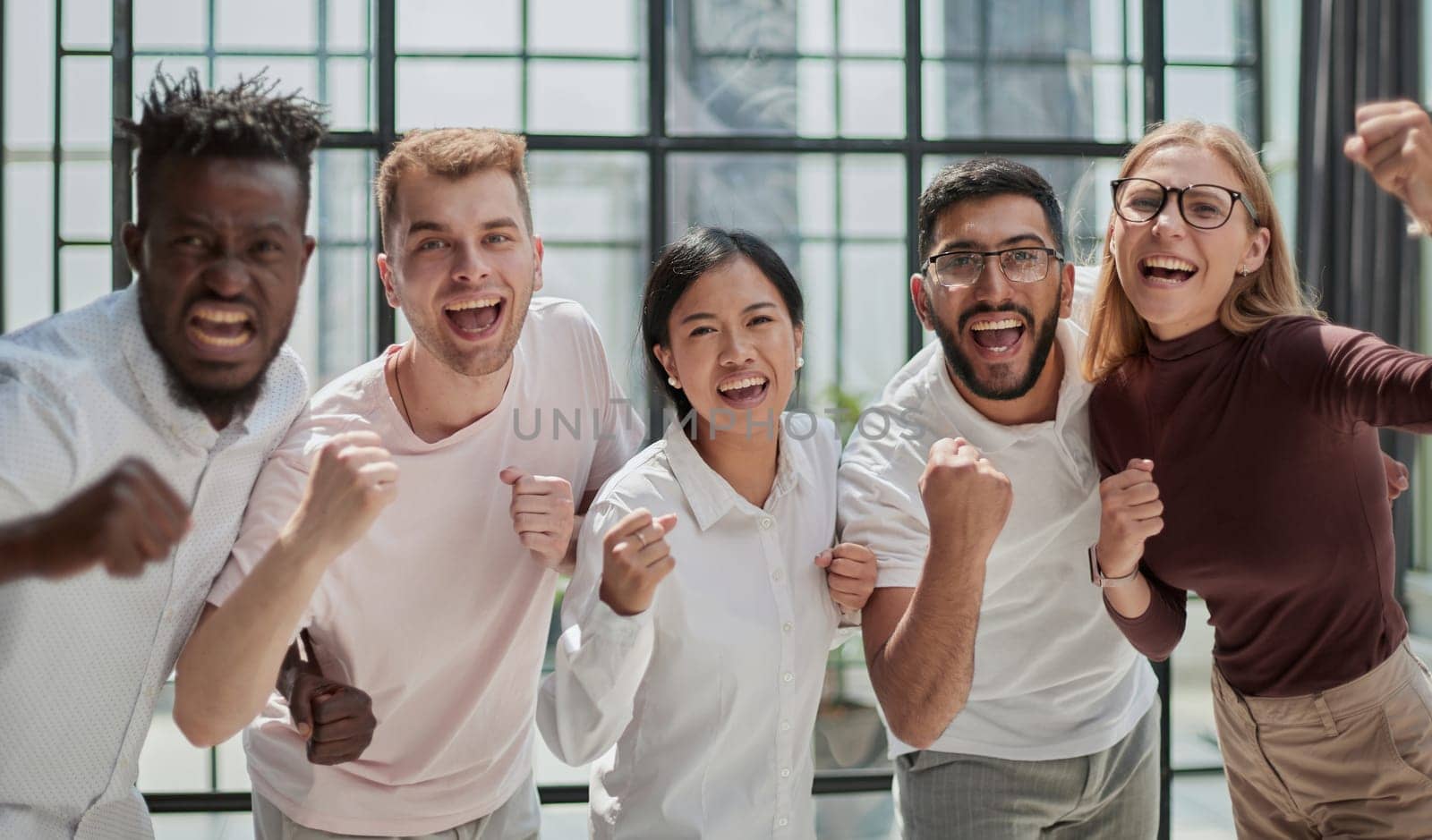 Group of mono-ethnic corporate employees clenching their fists celebrating success