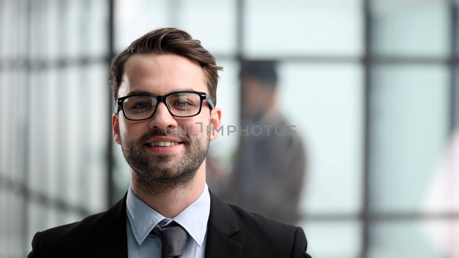 Smiling man in black suit against the backdrop of the office